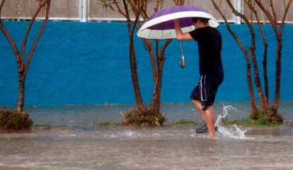 Una persona vadea una calle este viernes en la ciudad de Valencia cuando las provincias de Castellón y Valencia están en alerta naranja por precipitaciones de intensidad muy fuerte y con tormenta, que podrían acumular 40 litros por metro cuadrado en una hora, mientras que la provincia de Alicante está en nivel amarillo por precipitaciones acumuladas en 12 horas de 60 litros por metro cuadrado y de 30 litros por metro cuadrado en una hora.