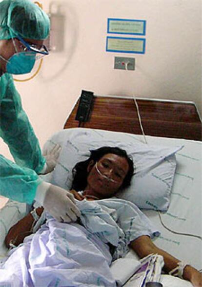 Un médico atiende a la tía de la niña muerta en Tailandia por la gripe aviar.