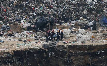 Bomberos transportan el cuerpo de una víctima del derrumbe en un basurero en Guatemala.