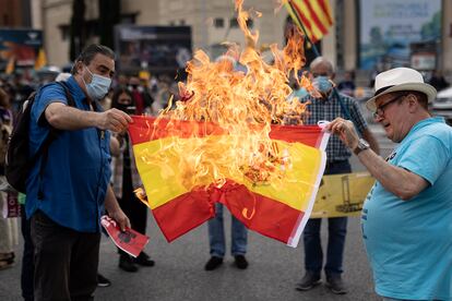 Dos manifestantes queman una bandera española durante la protesta.
