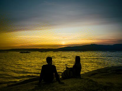Dos jóvenes observan la puesta de sol que culmina a las once de la noche desde Punta Cabalo, en A Illa de Arousa, donde se produce uno de los ocasos más tardíos en la Europa continental.