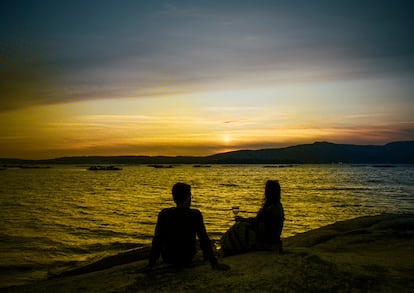 Dos jóvenes observan la puesta de sol que culmina a las once de la noche desde Punta Cabalo, en A Illa de Arousa, donde se produce uno de los ocasos más tardíos en la Europa continental.