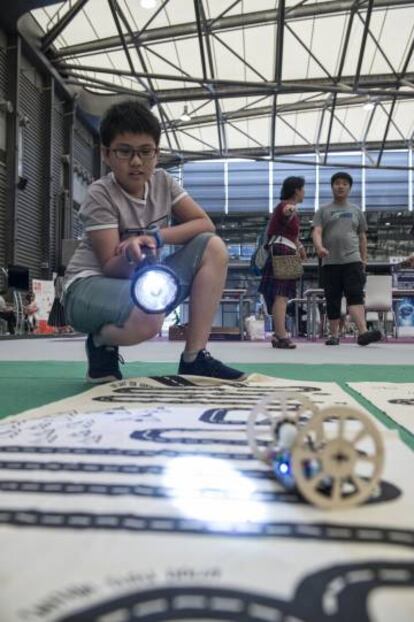 Menino se diverte com o robô guiado por luz que montou no TokyLabs.