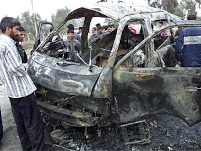 Un grupo de iraquíes, ante los restos de un vehículo destrozado por un atentado, ayer en Bagdad.