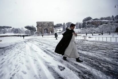 A pesar de las dificultades del trafico, romanos y turistas están disfrutando de la inusual nevada. En la foto, un cura cruza la calle nevada cerca del Arco de Constantino en Roma (Italia), el 26 de febrero de 2018.