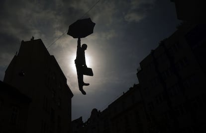 Escultura del artista checo Michal Trpak llamada 'Slight Uncertainity'. La obra que representa a un ejecutivo con un paraguas es un guiño a la crísis económica y está colgada en una calle de Praga, República Checa. 5 de mayo de 2014.