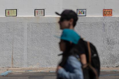 Dos jóvenes pasan por delante del IES Columela, en Cádiz, con carteles con expresiones típicas gaditanas.