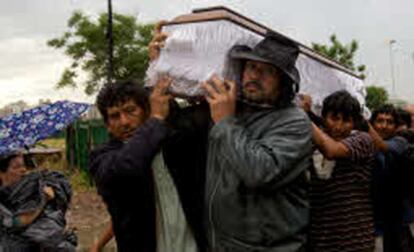 Ocupantes del parque en el barrio obrero de Villa Soldati, en Buenos Aires, llevan el féretro de uno de los inmigrantes muertos en los enfrentamientos que reclaman una vivienda.