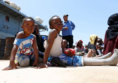 Dos niños sentados en la base naval de Tripoli tras ser restacados.