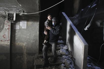 Un hombre ayuda a un niño a salir de un edificio en ruinas tras un ataque aéreo en el barrio de Al-Ansari en Alepo (Siria), 31 de enero de 2014.