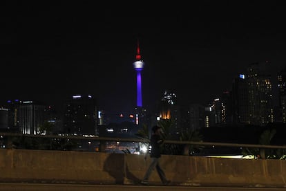 Un home passa amb un edifici emblemàtic de Kuala Lumpur (Malàisia) il·luminat amb els colors de la bandera francesa.