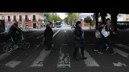 Peatones cruzan por un paso bajo el puente de la M30.