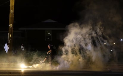 Un manifestante le da una patada a un bote de humo lanzado por la policia. El presidente Barack Obama hizo el martes una llamada a la calma