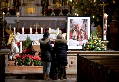 Dos personas ante el retrato de Benedicto XVI en la iglesia de Santa Magdalena en Altoetting (Alemania), este sábado.