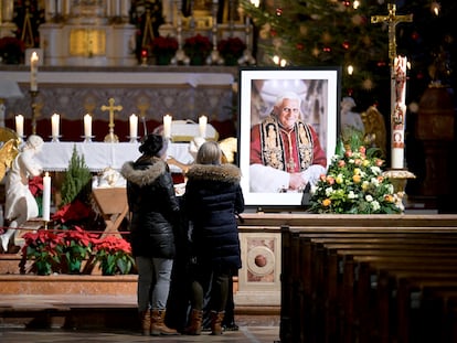 Dos personas ante el retrato de Benedicto XVI en la iglesia de Santa Magdalena en Altoetting (Alemania), este sábado.