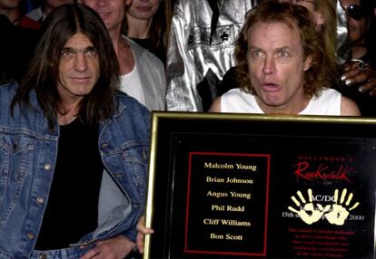 Los integrantes de la banda AC/DC Angus Young (derecha) y su hermano Malcolm muestra una placa después de dejar la huella en el Paseo de la Fama del Rock en Hollywood, en 2000.
