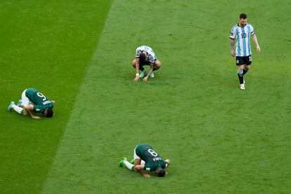 Leo Messi deja el campo mientras algunos jugadores saudíes rezan al término del partido.