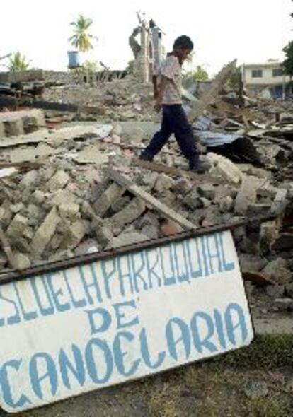 Un ni?o camina sobre los restos de la escuela Candelaria donde fallecieron la maestra y 20 escolares.