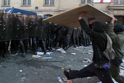 Dos estudiantes se enfrentan a la policía con una puerta de madera, durante los enfrentamientos ocurridos en los alrededores de La Sorbona. Tras la multitudinaria manifestación, cientos de jóvenes han ido a las inmediaciones de la universidad.