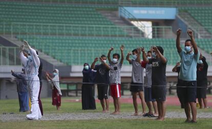 Un sanitario con un traje protector hace ejercicio con pacientes de covid-19 en el estadio Patriot Candrabhaga que se ha convertido recientemente en un centro de aislamiento para personas que muestran síntomas de la enfermedad en Bekasi, a las afueras de Yakarta, en Indonesia.