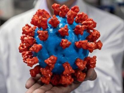 Un científico chino sostiene una réplica del coronavirus.