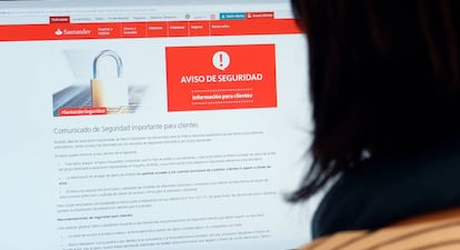 Una usuaria mira la p&aacute;gina web del Santander Espa&ntilde;a con el aviso de seguridad que explica el ataque inform&aacute;tico. Alex Onciu