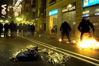 Policías tratan de apagar un fuego intencionado tras la marcha de Barcelona.