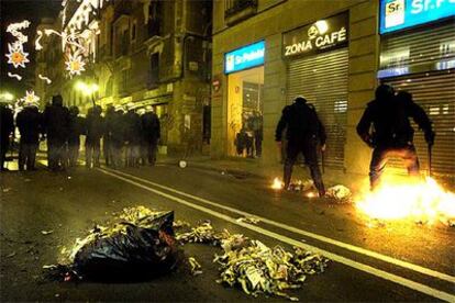 Policías tratan de apagar un fuego intencionado tras la marcha de Barcelona.