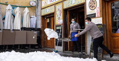 Personal de hostelería limpian de nieve las terrazas de los establecimientos en Madrid