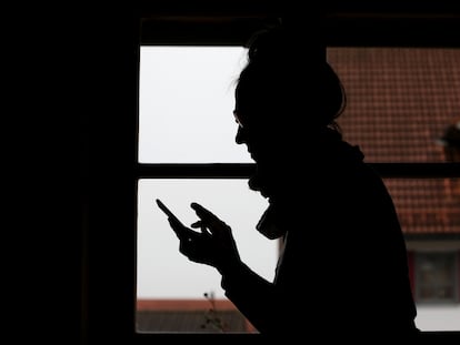 Una mujer usa su teléfono móvil en casa.