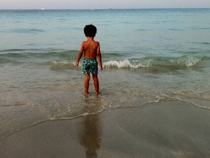 Un nen a punt de banyar-se en una platja.