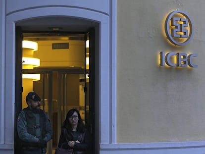 Una mujer abandona la sede del ICBC en España bajo la mirada de un agente de la Guardia Civil.