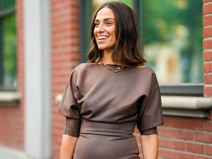 Mujer paseando con un vestido marrón chocolate por la calle.