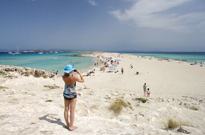 Una mujer fotografía la playa de Ses Illetes, en Formentera (Islas Baleares).