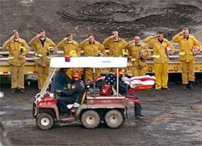 Bomberos saludan el cadáver, cubierto con una bandera, de un compañero muerto en el World Trade Center.