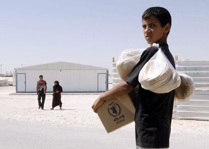 Un refugiado sirio carga con provisiones de alimento en el campo de refugiados sirios de Zatari.