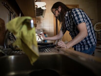 Un empleado teletrabaja desde su casa con un portátil mientras cocina.