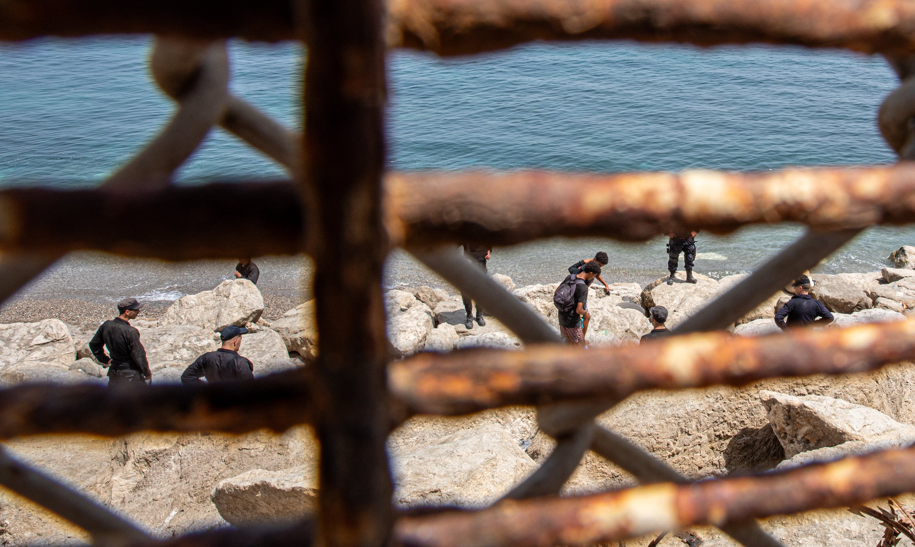 Policías marroquíes vigilan el retorno de jóvenes que han cruzado a Ceuta, el sábado en la valla de la frontera de Castillejos.