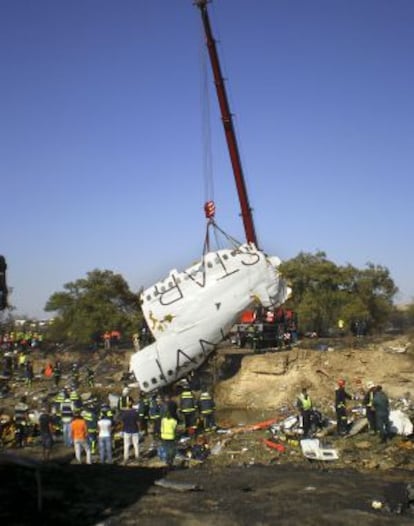 Una grúa levanta parte del fuselaje de la aeronave.