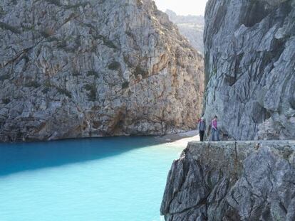 Senderistas en Sa Calobra, en la costa norte de Mallorca, con la cala del Torrent de Paréis asomando al fondo.