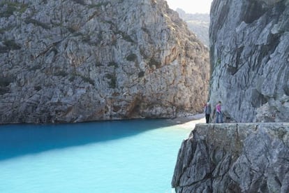 Senderistas en Sa Calobra, en la costa norte de Mallorca, con la cala del Torrent de Paréis asomando al fondo.