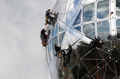 Trabajadores descienden por una de las nueve esferas del Atomium, estructura de 102 metros de altura construida para la Expo 58 en Bruselas, Bélgica.