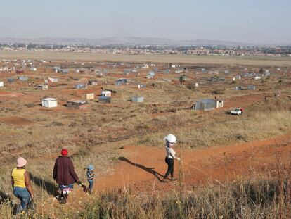 Una familia camina hacia una zona de asentamiento informal en Sudáfrica.