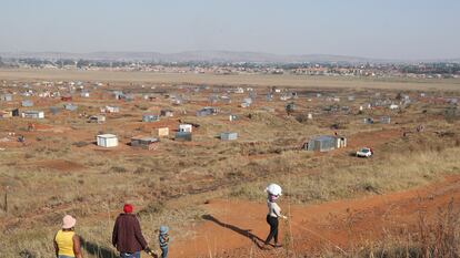 Una familia camina hacia una zona de asentamiento informal en Sudáfrica.