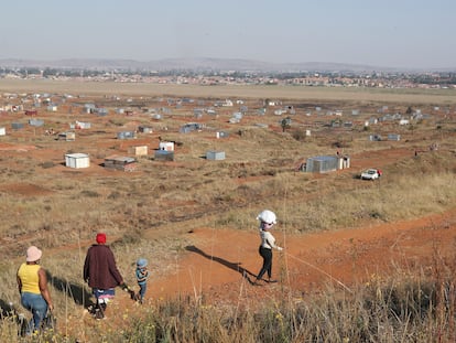 Una familia camina hacia una zona de asentamiento informal en Sudáfrica.
