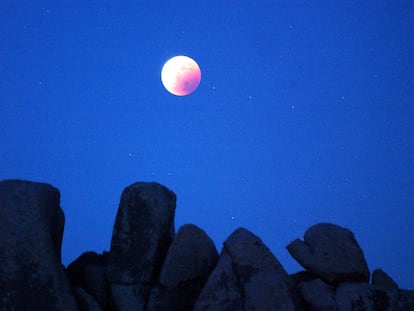 Una luna totalmente eclipsada brilla sobre formaciones rocosas en el desierto del Parque Nacional Joshua Tree, en California, EEUU, el 15 de mayo de 2003.
