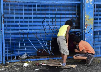 Dos ni&ntilde;os observan los destrozos en un supermercado tras una protesta. 