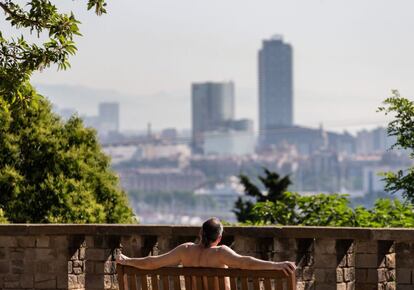 Un hombre toma el sol en un banco de un mirador de la montaña de Montjuïc, en Barcelona.