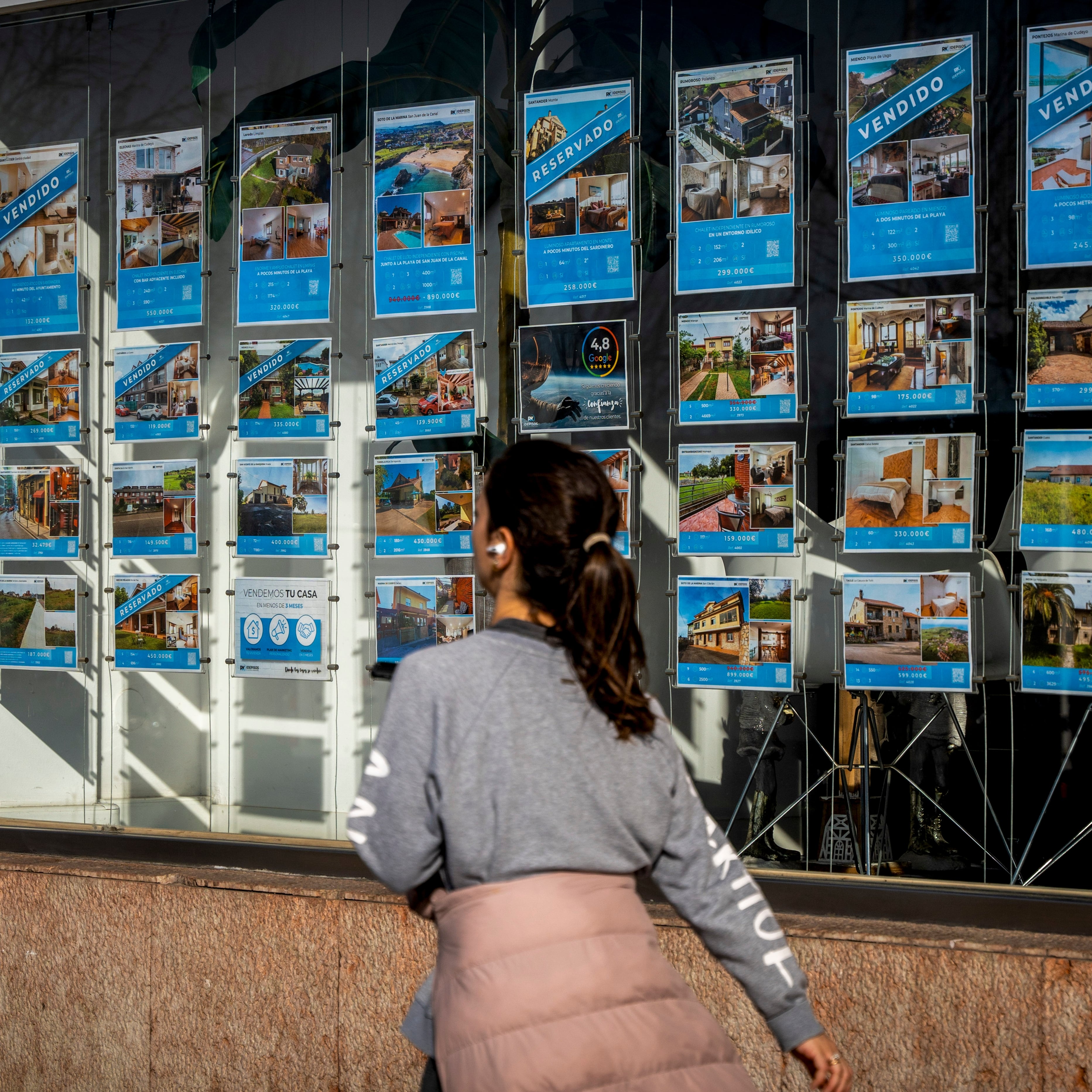 Una mujer pasa junto a una inmobiliaria en Santander.