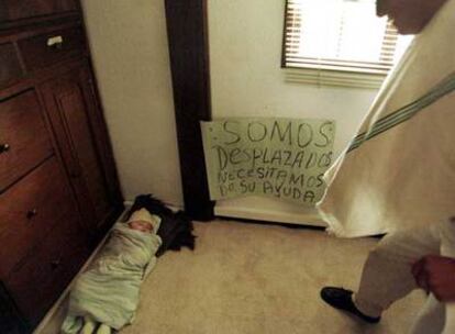 Un bebé refugiado duerme en el suelo junto a un cartel en el que los desplazados piden ayuda, en una foto de archivo.